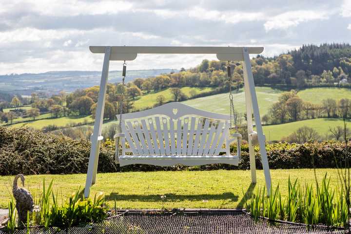 Garden swing seat situated over green hills and grass