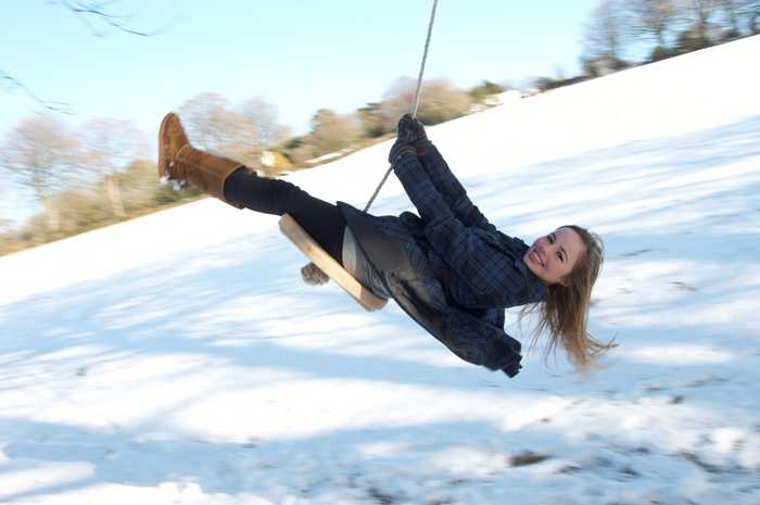 Girl swinging on the rope swing in the snow