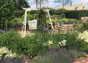 Looking across the herbacous border with a focal point of an Abinger Obelisk covered with Clematis
