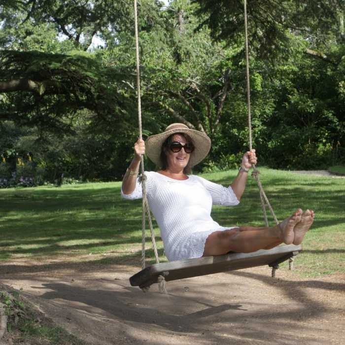 Mother and daughter swinging on a high quality swing seat hanging from a garden tree Mother and daughter swinging on a high quality swing seat hanging from a garden tree